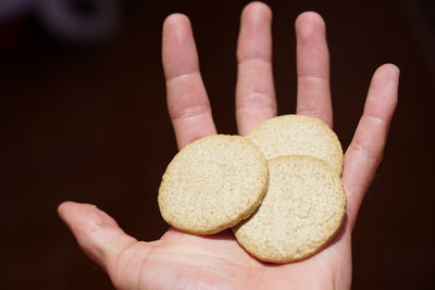 Close-up of hand holding cookies against black background