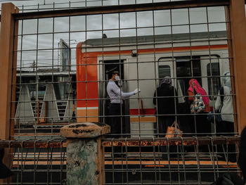 Woman standing by railing against window