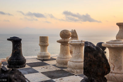 Chess pieces by sea during sunset