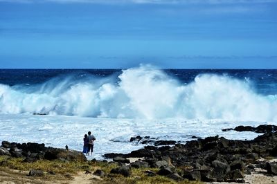 Rear view of couple watching waves of sea