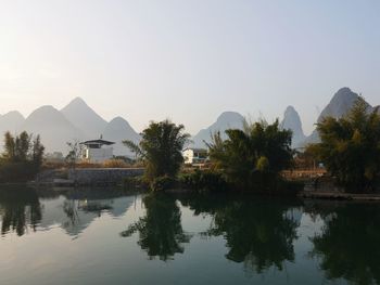 Reflection of trees and buildings in lake against sky