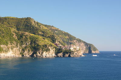 Scenic view of sea and mountains against clear blue sky