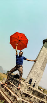 Low angle view of man holding umbrella against sky