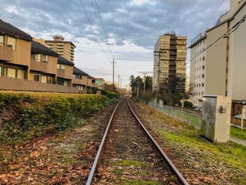 Railroad tracks by buildings against sky