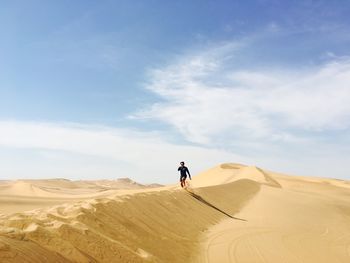 Young man running on desert against sky