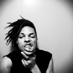 Portrait of young man making face against wall at home