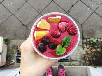 Low section of woman holding dessert while standing on street