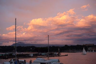 Boats at harbor against cloudy sky