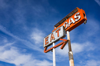 Low angle view of sign against blue sky