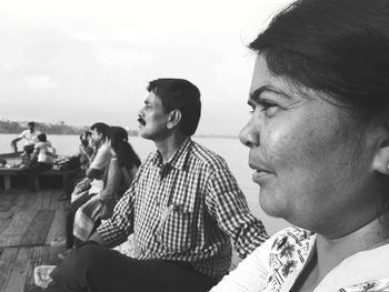 Side view of mature man and woman sitting on pier over river