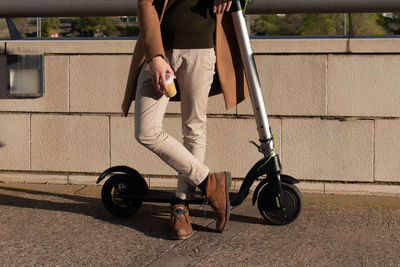 Cropped shot of young bussinesman on electric scooter from work with take away coffee cup spare time
