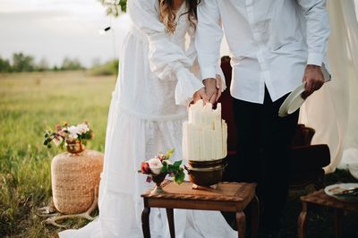 Bride and groom cutting cake on field