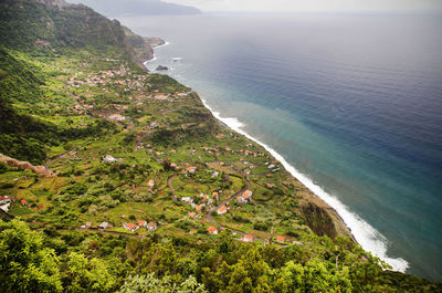 Aerial view of houses and trees on mountain by seascape