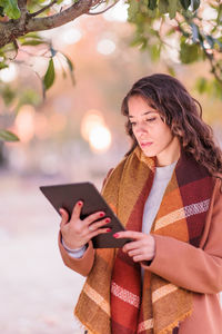 Portrait of young woman standing against trees