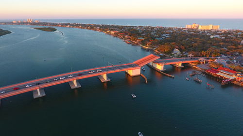 Aerial view of bridge over river against sky at sunset