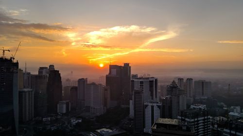 Modern buildings in city against sky during sunset