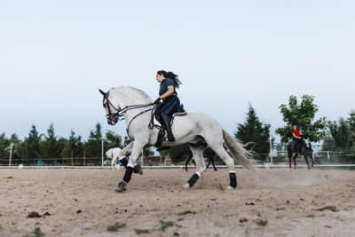 Young female friends riding horse in farm during weekend