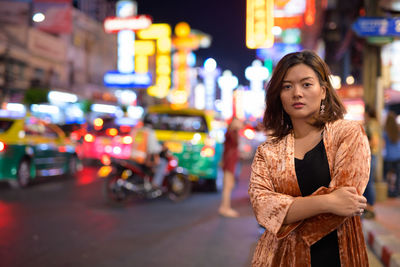 Young woman standing on city street at night