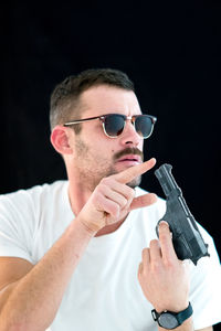 Man touching gun against black background