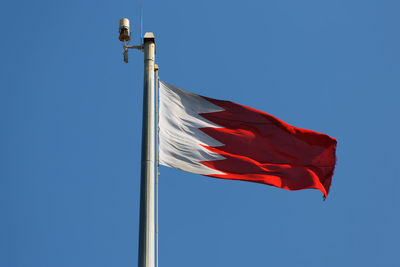 Low angle view of bahraini flag against blue sky