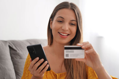 Young woman using mobile phone against white background