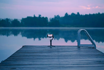 Pier over lake against sky during sunset