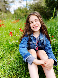 Portrait of young woman sitting on grassy field