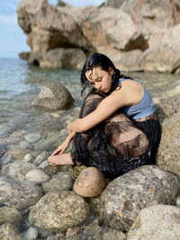 Young woman sitting on rock at beach