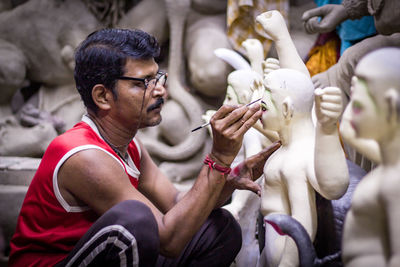 Side view of man holding statue