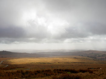 Thick clouds lighting a part of the grassy moors of dartmoor. devon, united kingdom.