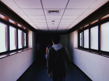 Rear view of man and woman walking in illuminated building