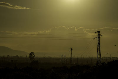 Silhouette electricity pylon against sky during sunset