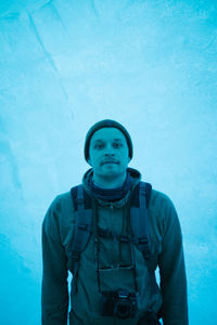 Portrait of young man standing against blue wall