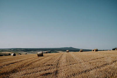 Hay bales on field against clear sky