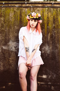 Young woman standing against wall