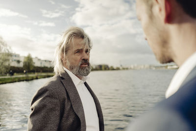 Senior businessman at a lake talking to man in foreground