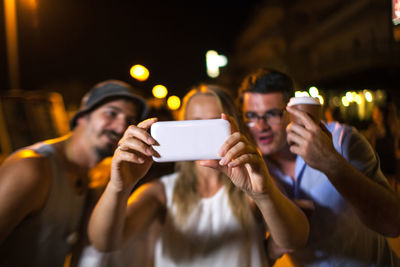 Cheerful friends taking selfie at night