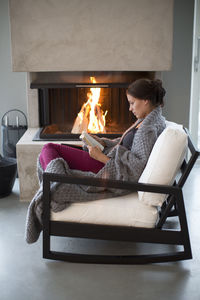 Young woman sitting in front of fireplace and reading