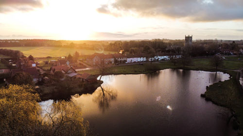 Scenic view of river by buildings against sky during sunset