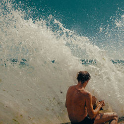 Wave splashing on man at beach