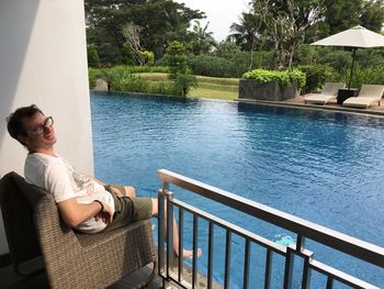 Man sitting by swimming pool against sea