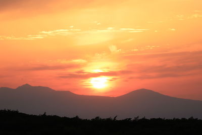 Scenic view of silhouette mountains against romantic sky at sunset