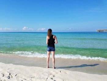 Rear view of woman standing at beach on sunny day