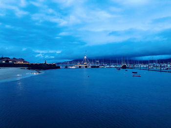 Sailboats in sea against cloudy sky