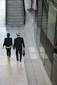 Rear view of male and female colleagues walking in lobby