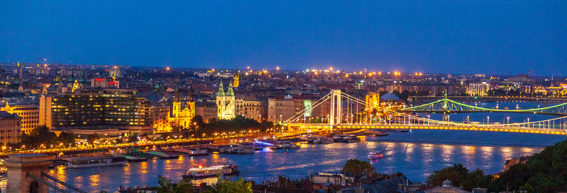 Illuminated city by river against sky at night