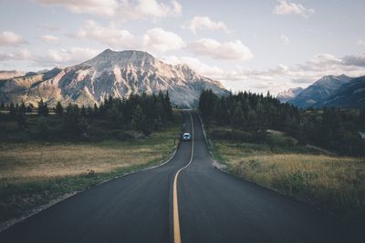 Road amidst field leading towards mountain