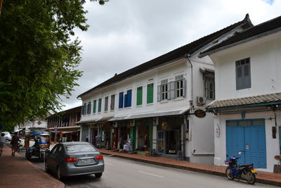 Cars on street by buildings in city against sky