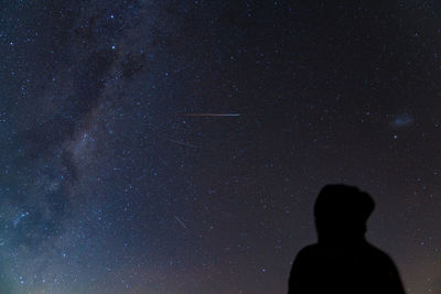 Low angle view of silhouette man against star field at night