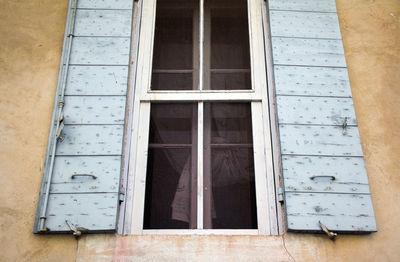 Old blue shutters and closed window, curtains, weathered, natural light, background